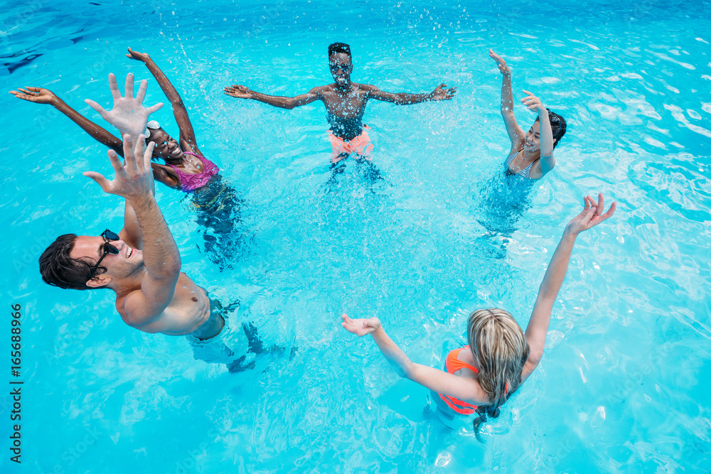 Group of young happy multiethnic people having fun together in swimming pool