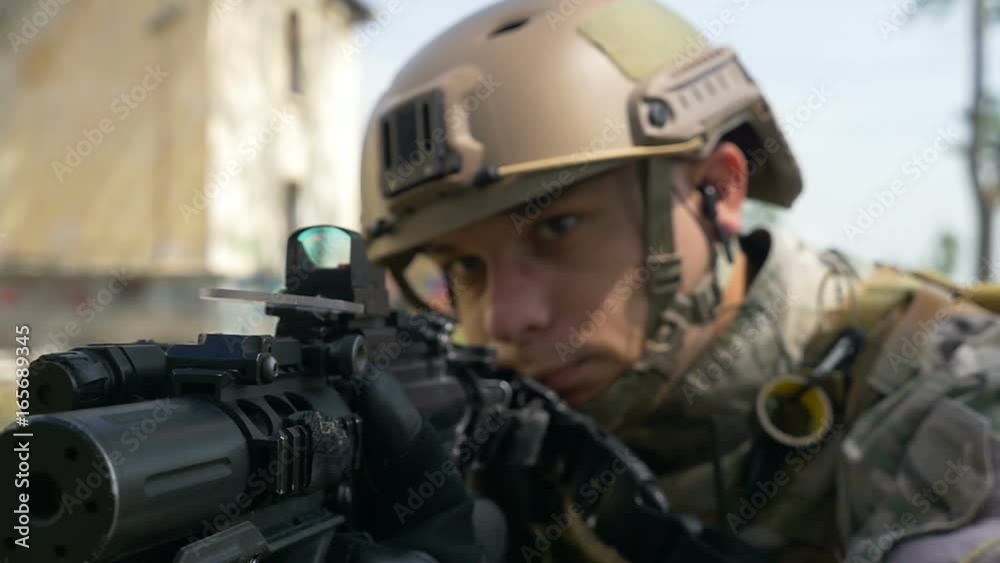 Slow motion of soldier with gun and headset aiming target in tactical operation ready for firing Slow motion of soldier with gun and headset aiming target in tactical operation ready for firing