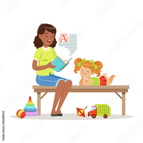 Teacher reading a book to little girl while sitting on a bench, girl enjoy listening, kids education and upbringing in preschool or kindergarten, colorful characters