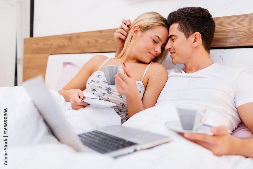 Couple in love holding coffee while in bed Couple in love holding coffee while in bed