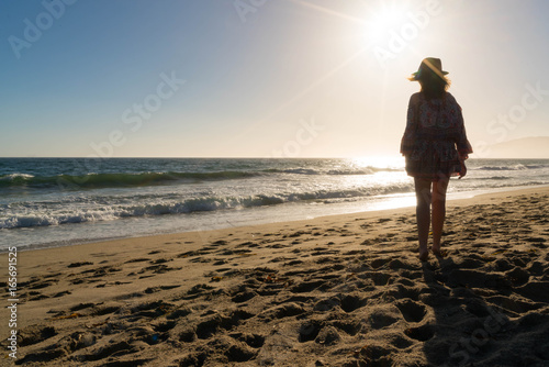 Woman watches Setting Sun at Beach 