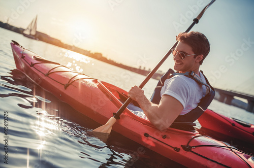 Man kayaking on sunset photo