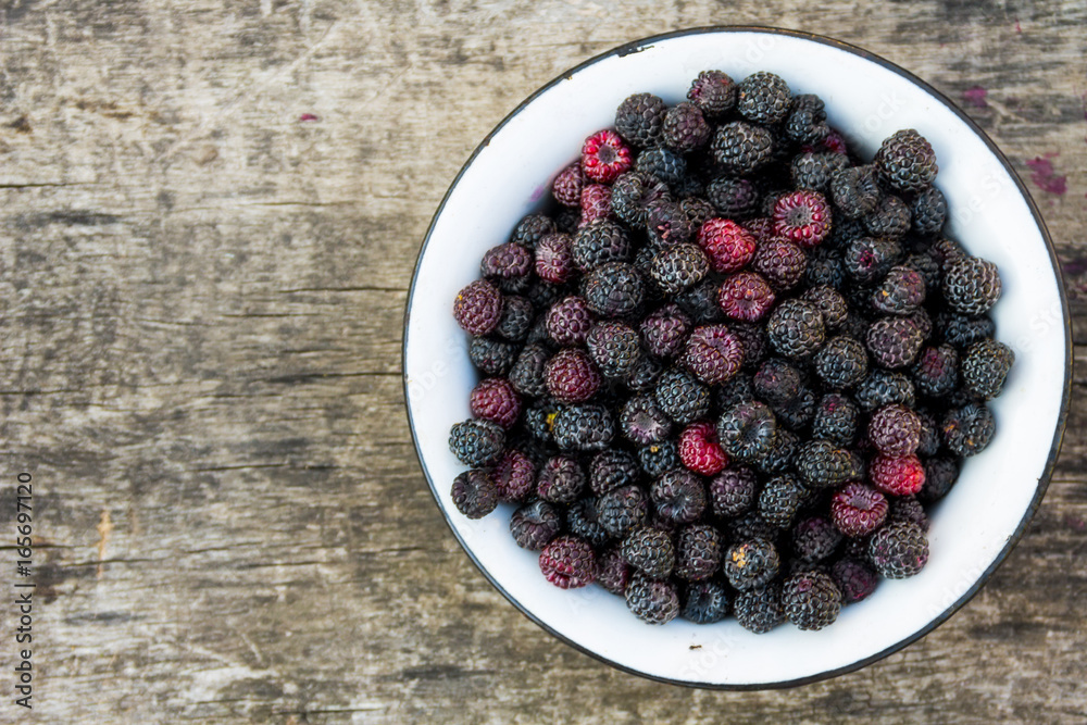 Ripe blackberries in rustic bowl on old wooden background. Top view Ripe blackberries in rustic bowl on old wooden background. Top view