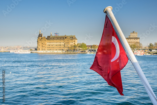 View of historical train terminal named Haydarpasa from Traditional public ferry .Until 2012 the station was a major intercity, regional and commuter rail hub in Turkey.Turkish flag on foreground