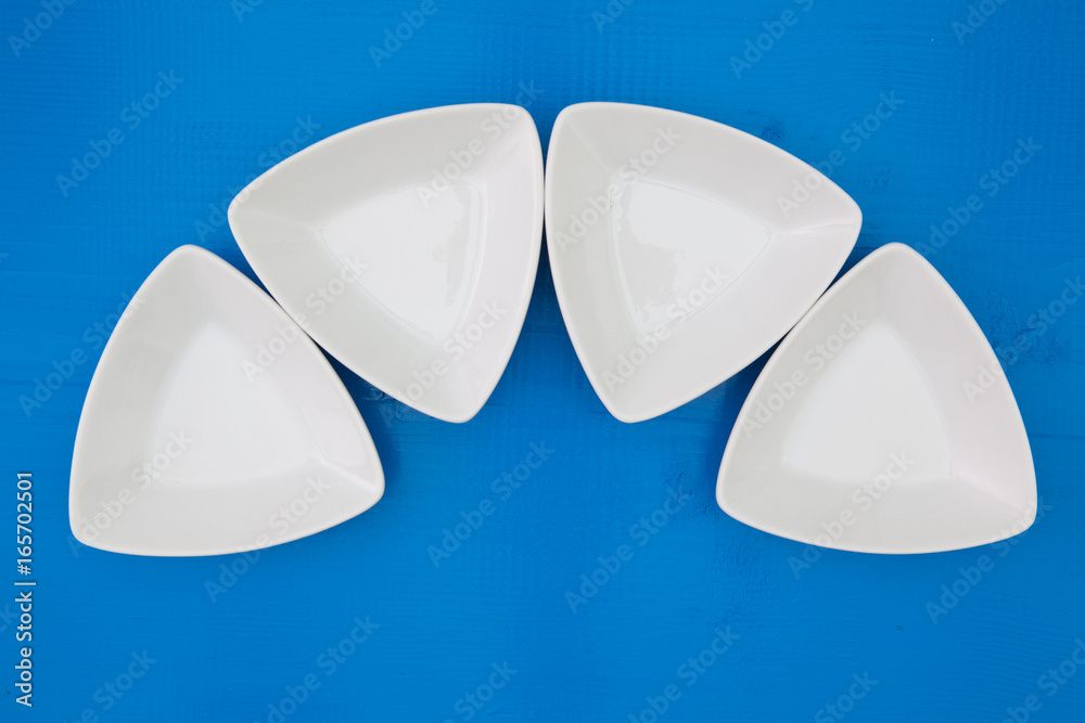 Empty triangular ceramic bowls for sushi on the blue wooden table Empty triangular ceramic bowls for sushi on the blue wooden table