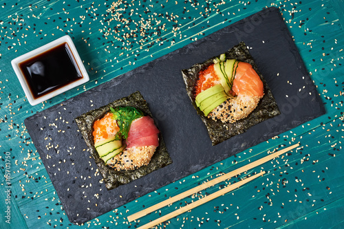Sushi donuts on wooden board with ginger on black background