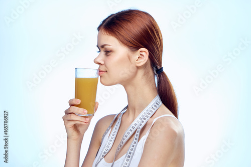 Young beautiful woman on a blue background holds a glass of fresh juice, diet, fitness