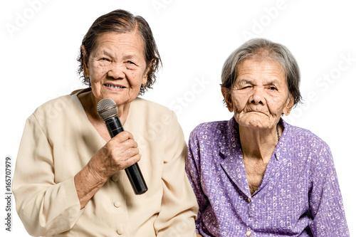Portrait of two senior asian women sing a song into microphone. Isolated on white background with clipping path