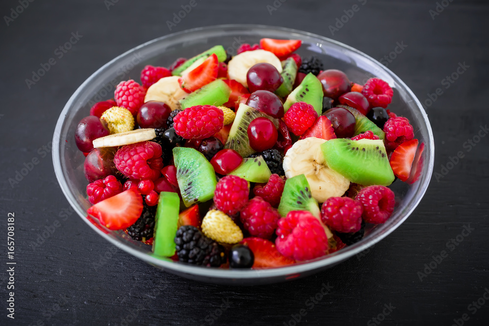 Natural breakfast, fruit salad in glass plate on dark background. Natural breakfast, fruit salad in glass plate on dark background.