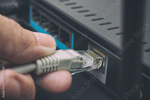 Person plugging in cable to wireless router photo