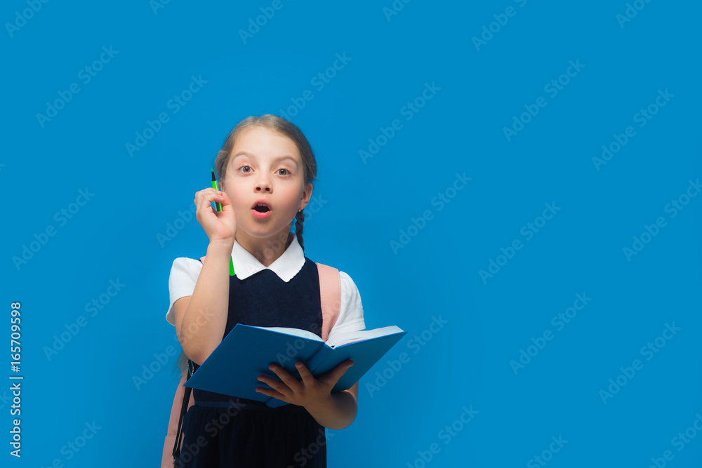 Girl with braids having idea. Pupil holds big blue book Girl with braids having idea. Pupil holds big blue book