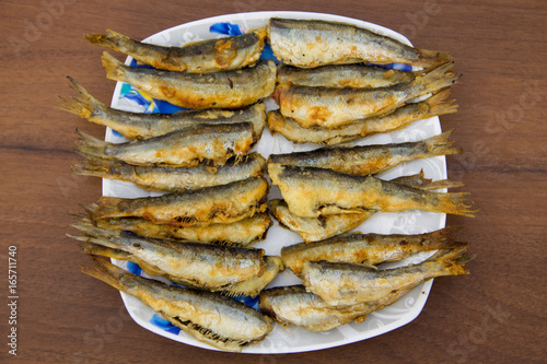 Fried baltic herring on a plate on wooden background