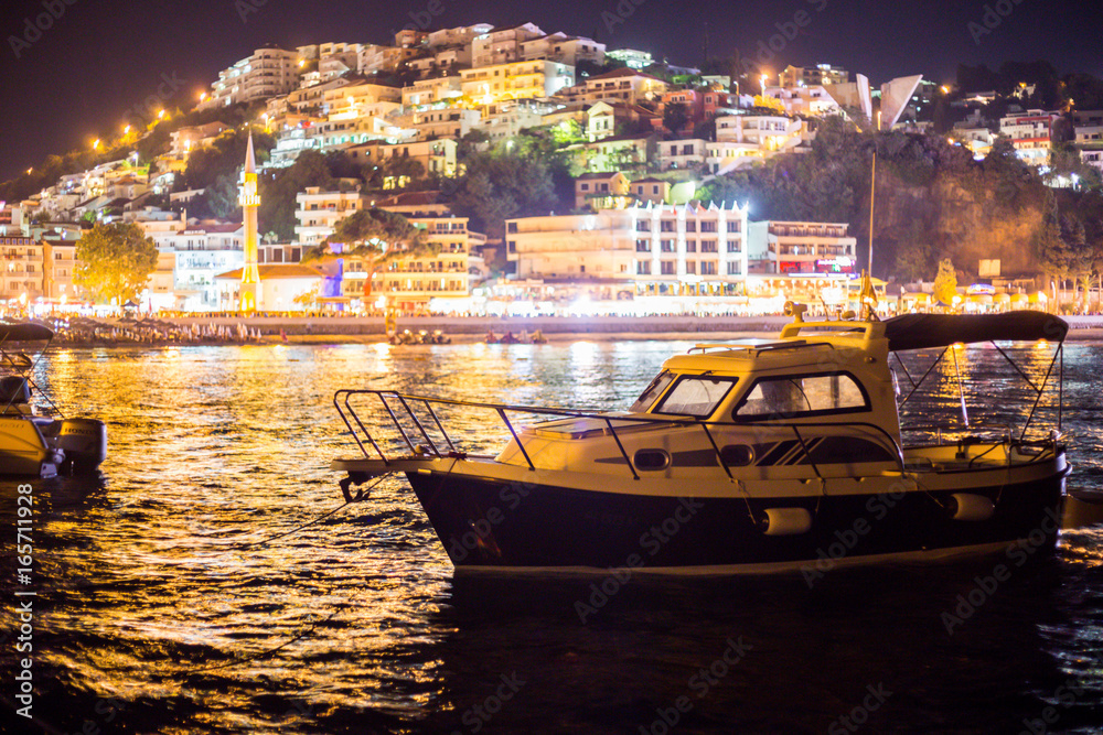 Closeup of a boat on sea with city lights in the background in the evening Closeup of a boat on sea with city lights in the background in the evening