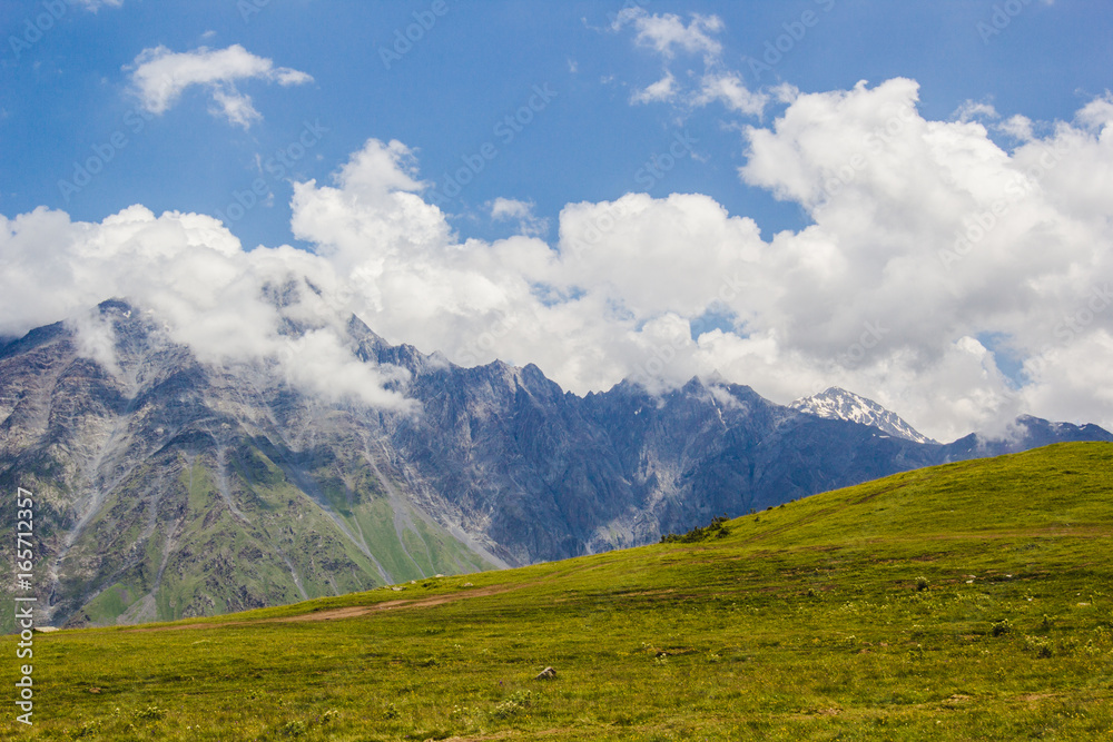 Rocky Caucasus mountains in Kazbeki region with cloudy blue sky background Rocky Caucasus mountains in Kazbeki region with cloudy blue sky background