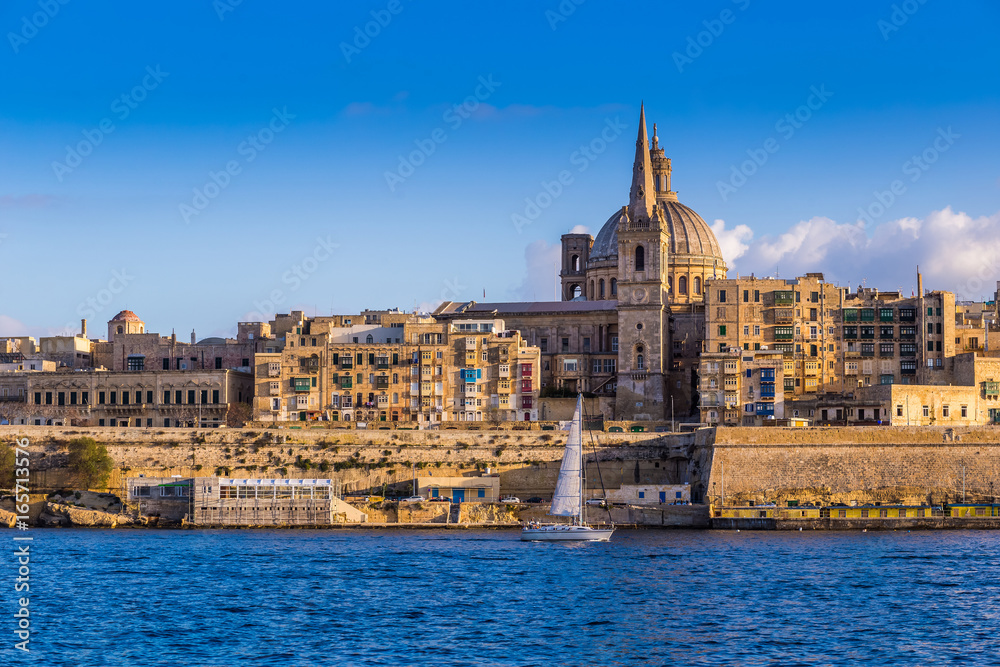 Valletta, Malta - Saint Paul's Cathedral and the ancient walls of Valletta with sail boat in the morning