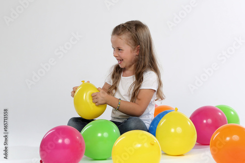 Kind sitzend zwischen Ballons lacht