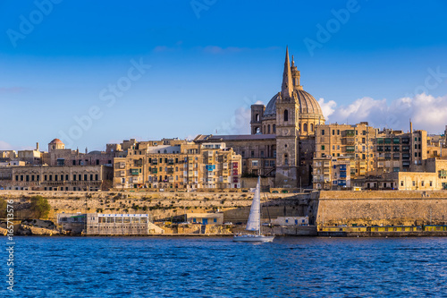 Valletta, Malta - Saint Paul's Cathedral and the ancient walls of Valletta with sail boat in the morning