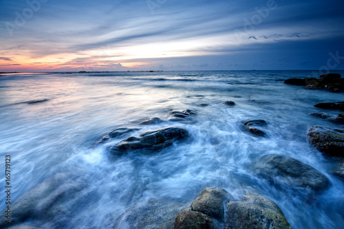 Colorful sunset with natural coastal rocks. Image contain soft focus due to long exposure.
