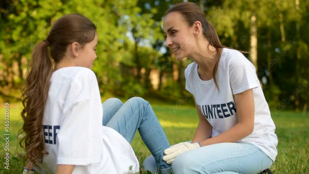 Smart little lady chatting over something with female volunteer Smart little lady chatting over something with female volunteer
