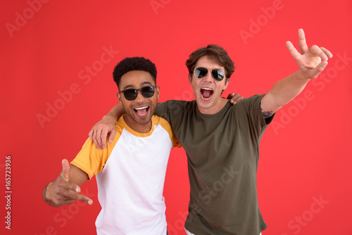 Young two men friends isolated over red background