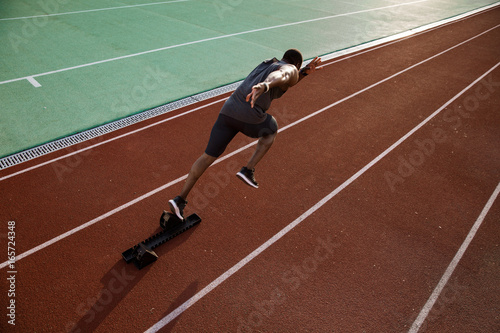 Young african male runner running on racetrack