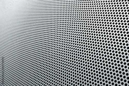 Gray metal background, round perforated metal texture with reflections