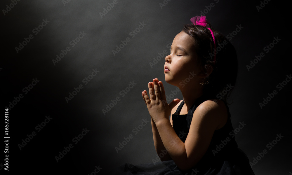 Little girl praying, isolated black background Stock Photo Adobe Stock