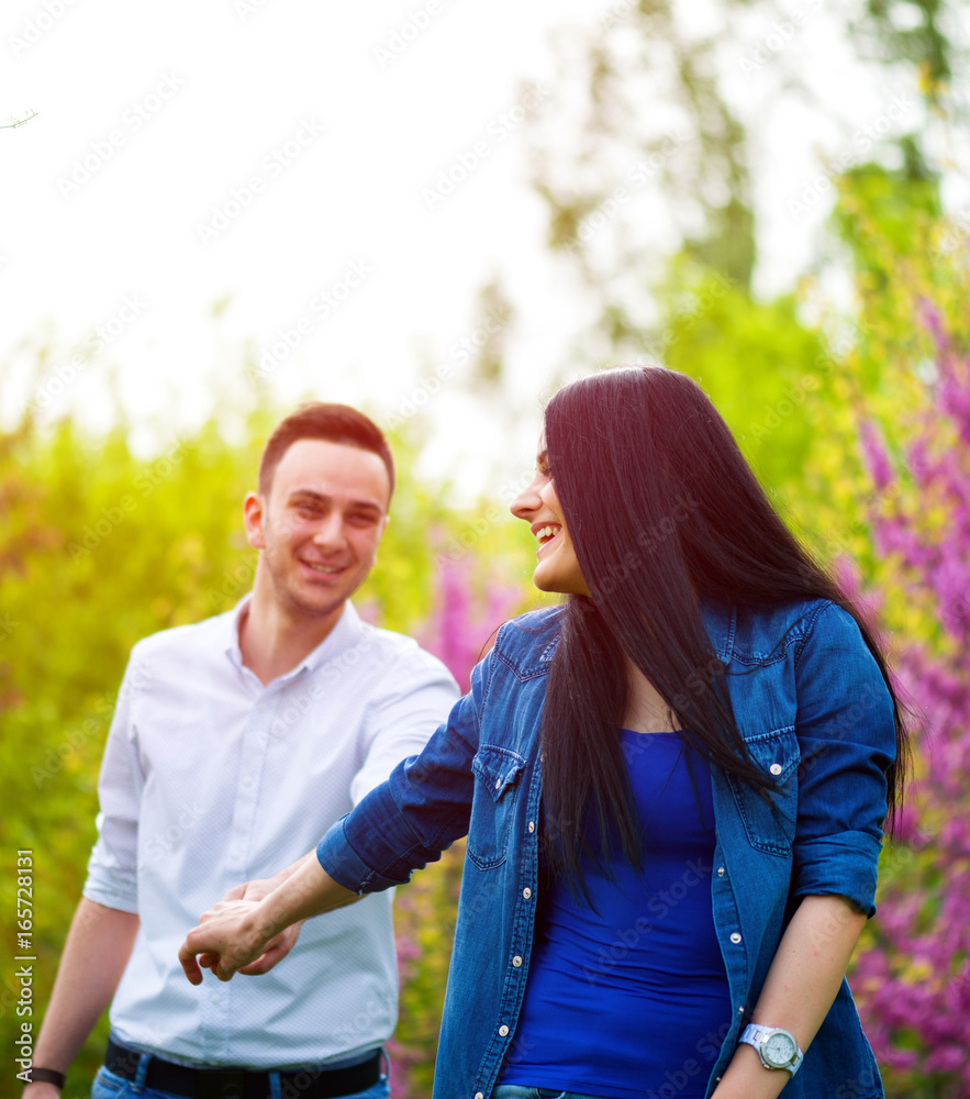 Obraz premium young woman holding man's hand and leading him on nature outdoor
