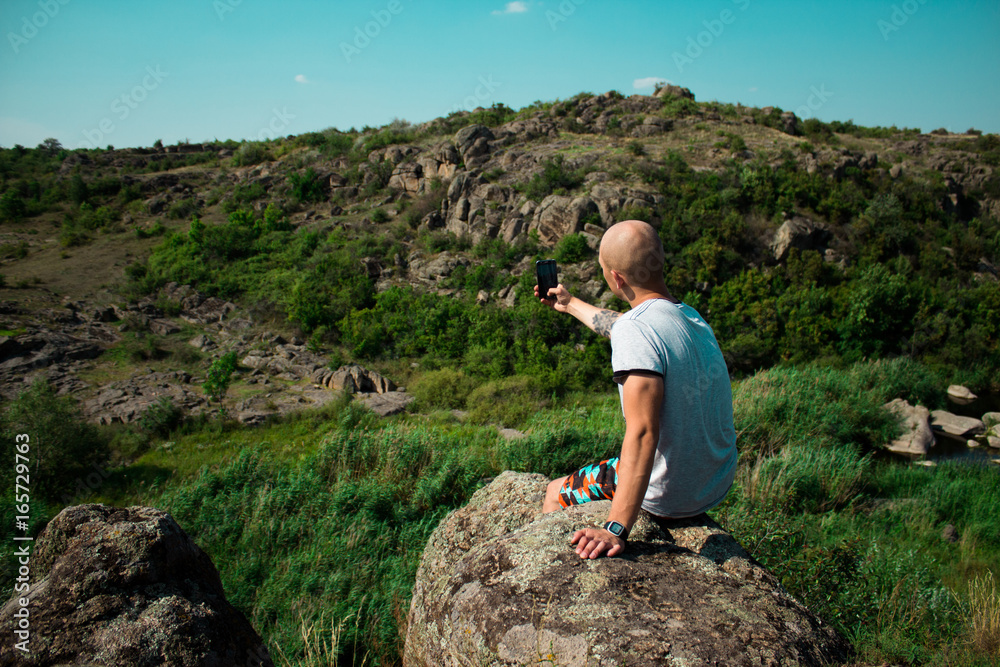 Naklejka premium Tourism concept. Young man taking photo on smartphone while traveling