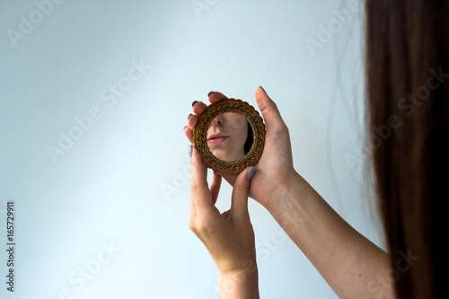 young beautiful girl looking in the mirror in the white background
