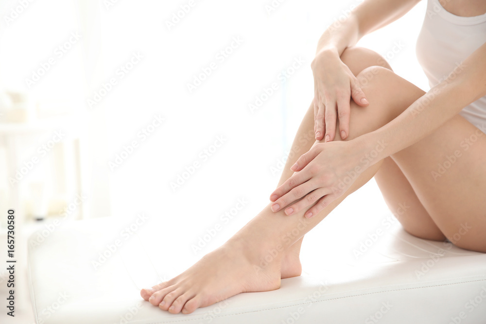 Young woman touching smooth skin on leg, indoors. Epilation concept Young woman touching smooth skin on leg, indoors. Epilation concept