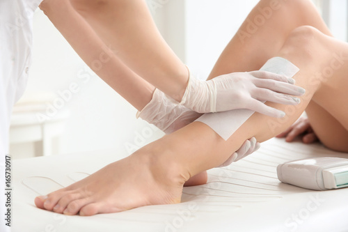Woman having hair removal procedure on leg with wax depilatory in salon. Depilation concept