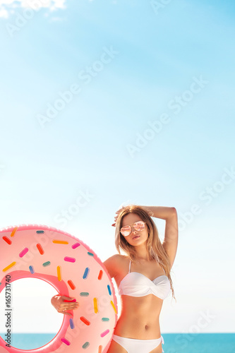 Summer Vacation. Enjoying suntan woman in white bikini with donut mattress near the swimming pool. © Mike Orlov