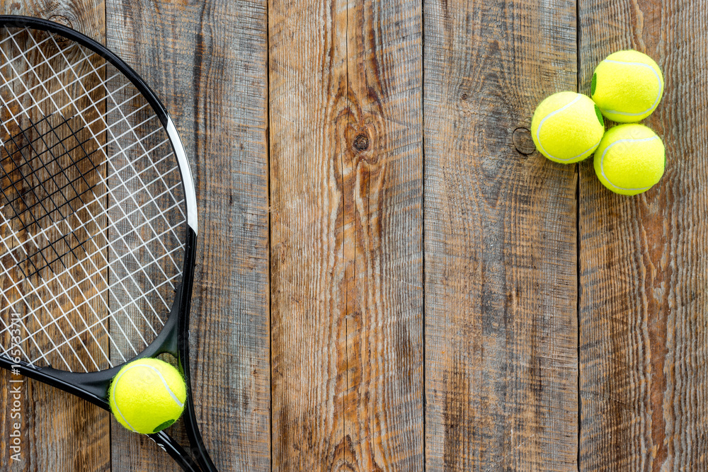 Sport background. Tennis balls and racket on wooden background top view copyspace