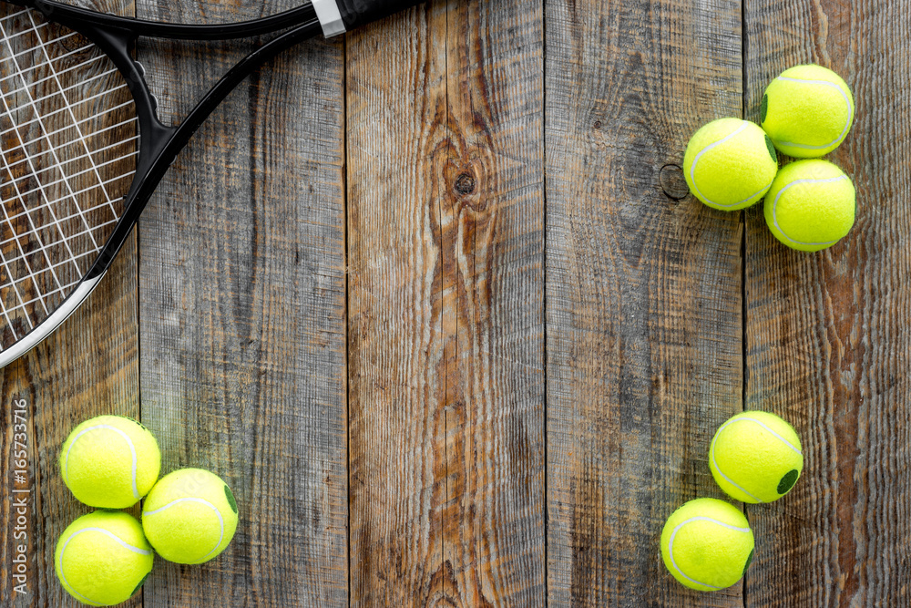 Sport background. Tennis balls and racket on wooden background top view copyspace