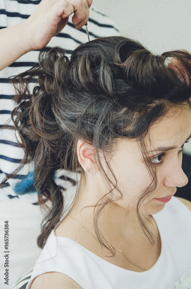 A professional hairdresser makes a festive hairstyle for the girl. Close-up. A professional hairdresser makes a festive hairstyle for the girl. Close-up.