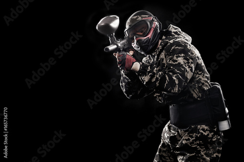 Fototapeta Naklejka Na Ścianę i Meble -  Heavily armed masked soldier isolated on black background. Paint ball and laser tag sport games.