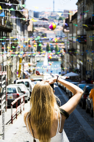 Young woman photographing colorful street in Porto, Portugal