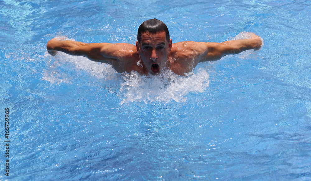 Strong muscular man swimming in pool butterfly style. Active summer holiday vacation. Sport, healthy lifestyle concept