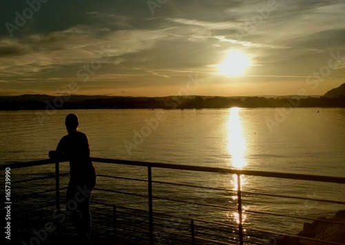 fille qui regarde un coucher de soleil sur le lac d'Annecy