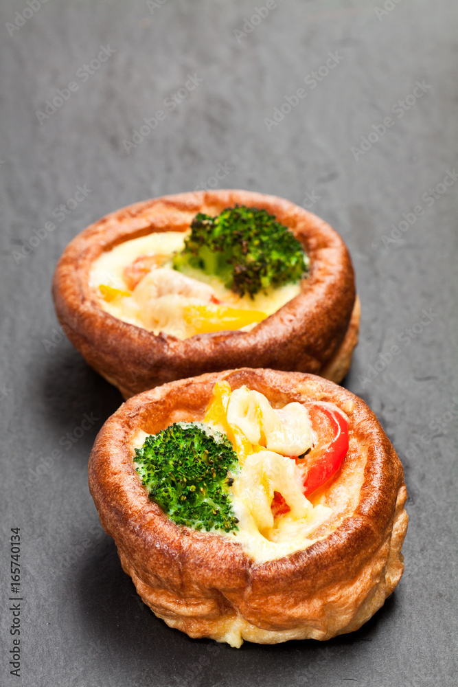 Yorkshire puddings stuffed with broccoli and scrambled eggs on black stone background Yorkshire puddings stuffed with broccoli and scrambled eggs on black stone background
