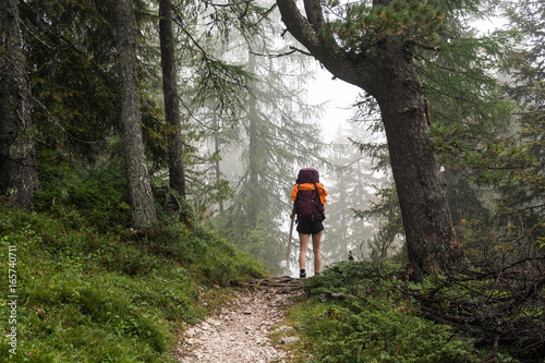 Young woman hiking in forest in dolomite mountains, Italy © Oliver
