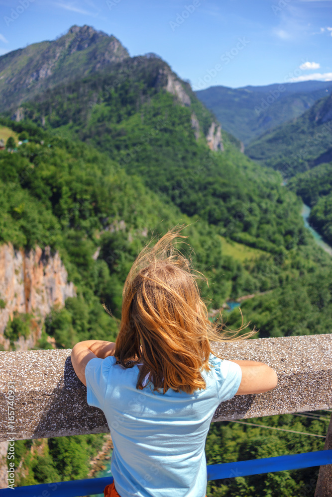 the girl looks from the bridge to the canyon