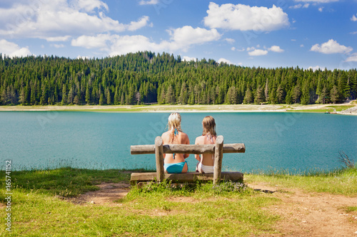 two girls on a bench near the lake