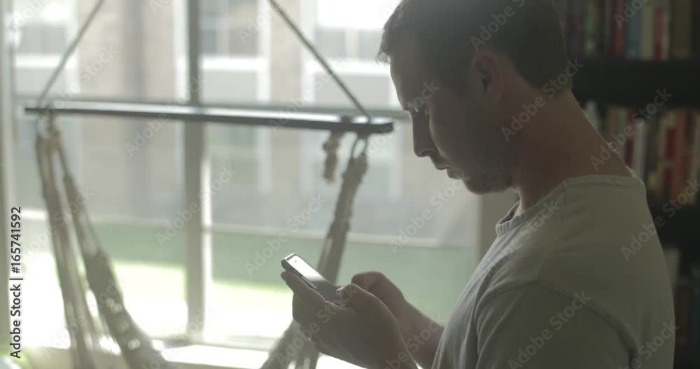 A man uses his smart phone to send a text while at home.