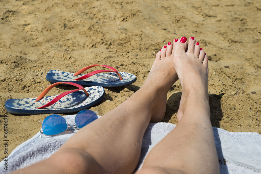 Foto de Young girl legs and flip-flop on the sand beach in summer do Stock