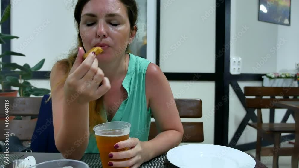 The girl is drinking beer in the bar. Woman drinks beer and eats fish rest The girl is drinking beer in the bar. Woman drinks beer and eats fish rest