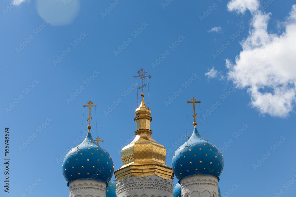 Golden domes of the Russian Сhurch against a blue sky with clouds