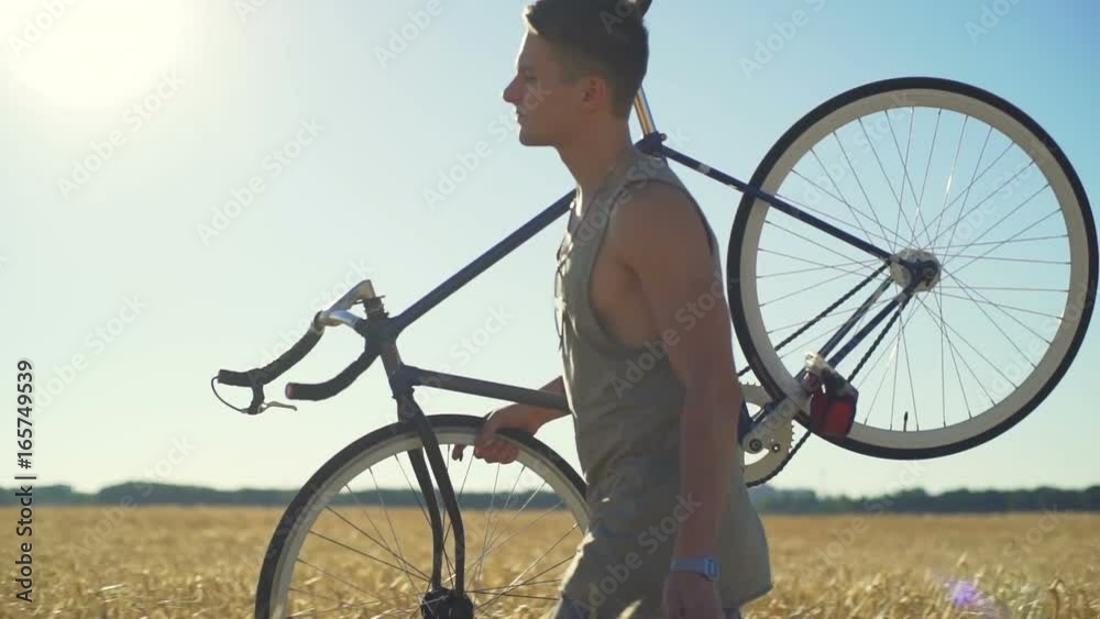 Beautiful man walk field with his bicycle touch wheat sundown slow motion rapid
