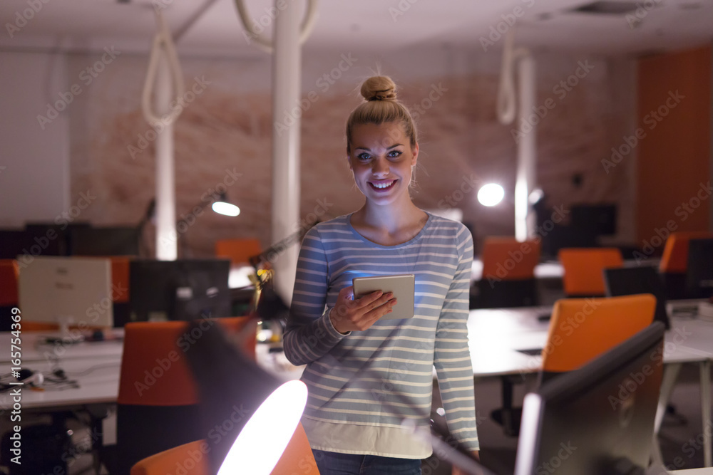 woman working on digital tablet in night office